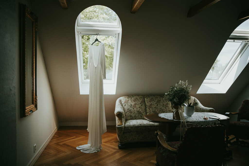 Brudekjole som heng i eit historisk rom på Bekkjarvik Gjestgiveri